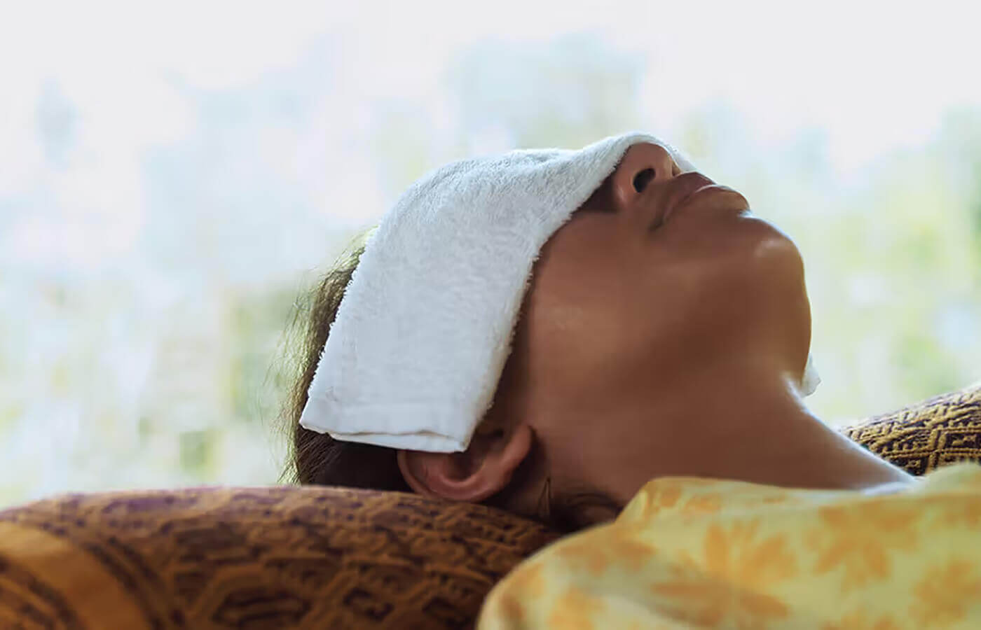 A girl puts a hot towel soaked in hot water on her eyes