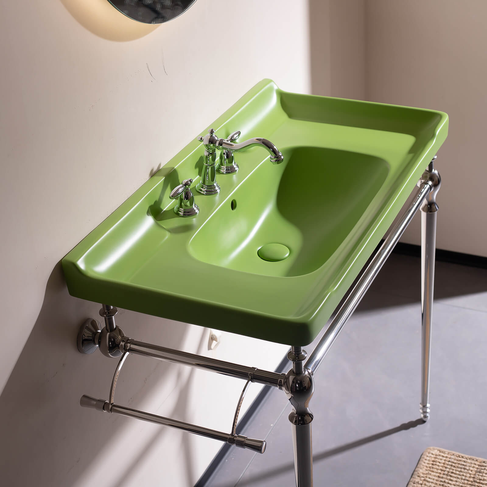 Console style bathroom sink with chrome legs and muted green ceramic basin