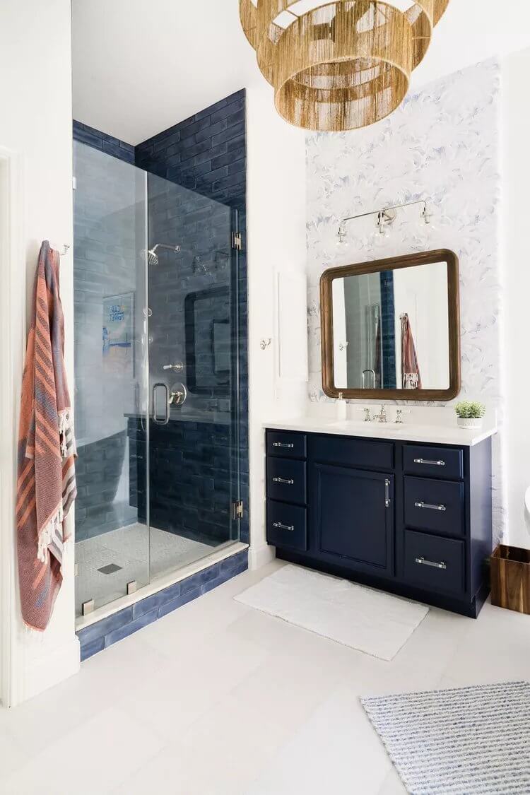 Elegant navy blue bathroom vanity with watercolor wallpaper, neutral walls, and mixed blue tiles in a luxurious yet calming primary bathroom