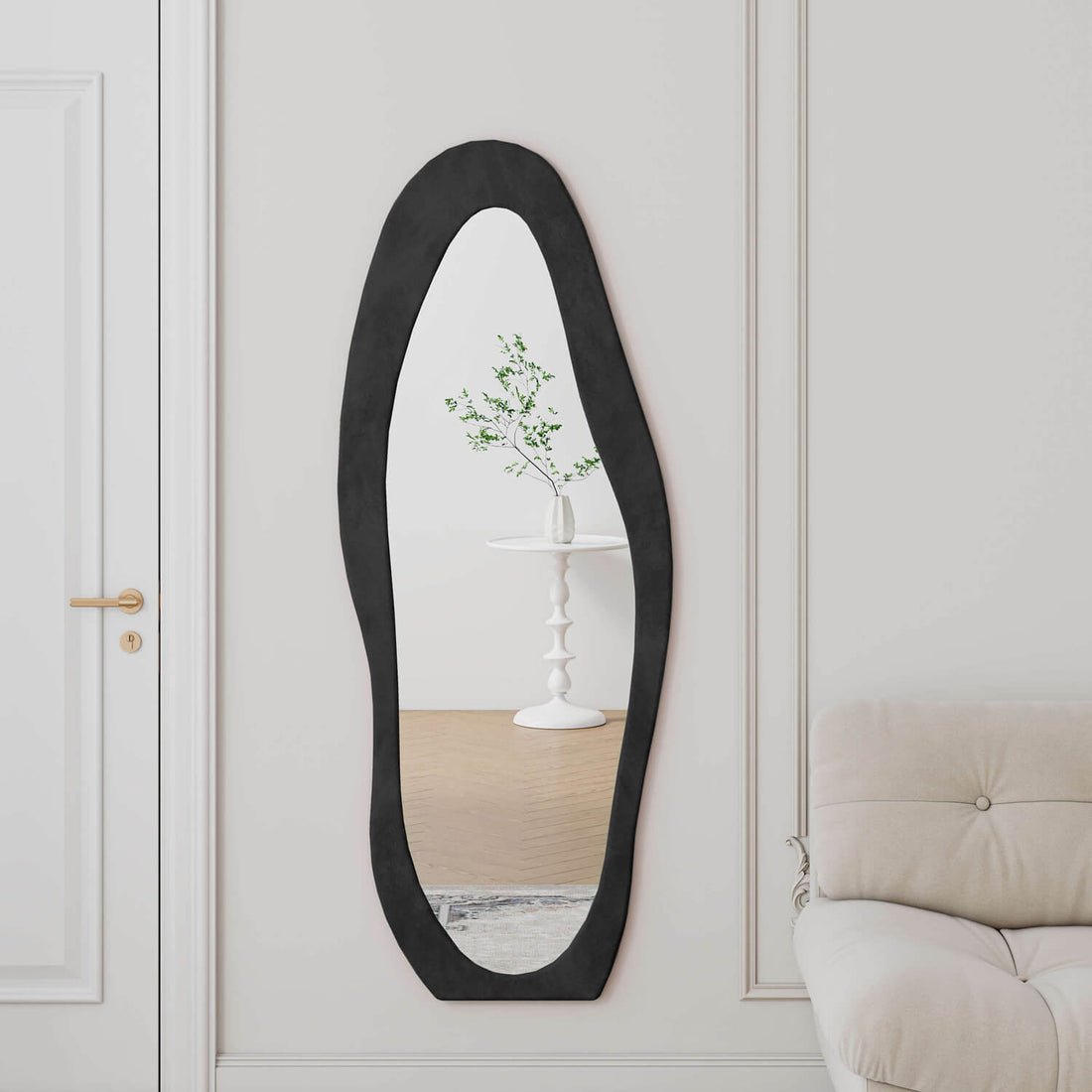 Wall mounted organic shape black mirror reflecting plant in French entryway