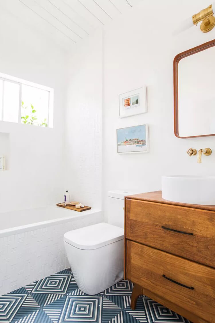 weathered wood cabinet paired with two different tile patterns and crisp white walls, it creates a layered, lived-in look that feels both bright and welcoming