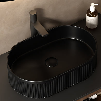 Black oval ceramic vessel bathroom sink with striped exterior, smooth interior, central drain, and above-counter mount