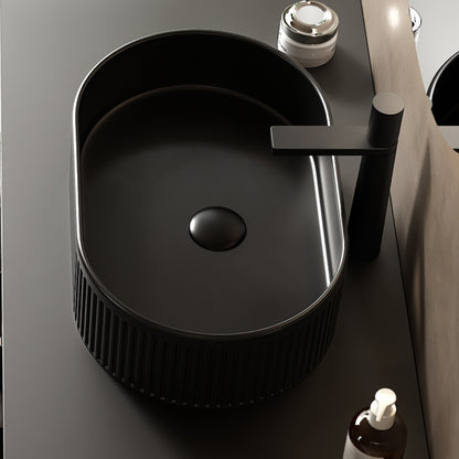 Black oval ceramic vessel bathroom sink with textured striped exterior, smooth interior, and above-counter installation
