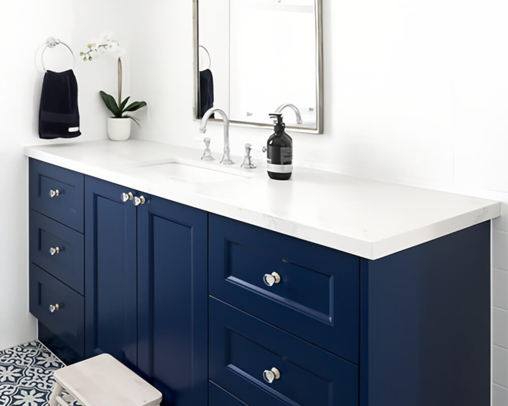 Navy blue bathroom vanity with white marble countertop, silver hardware, Moroccan blue-and-white tile floor, and modern silver-framed mirror