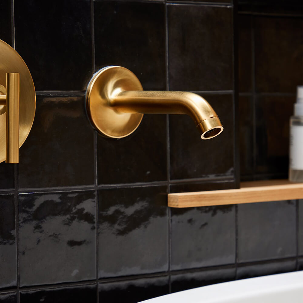 Soaking tub with gold wall-mounted faucet