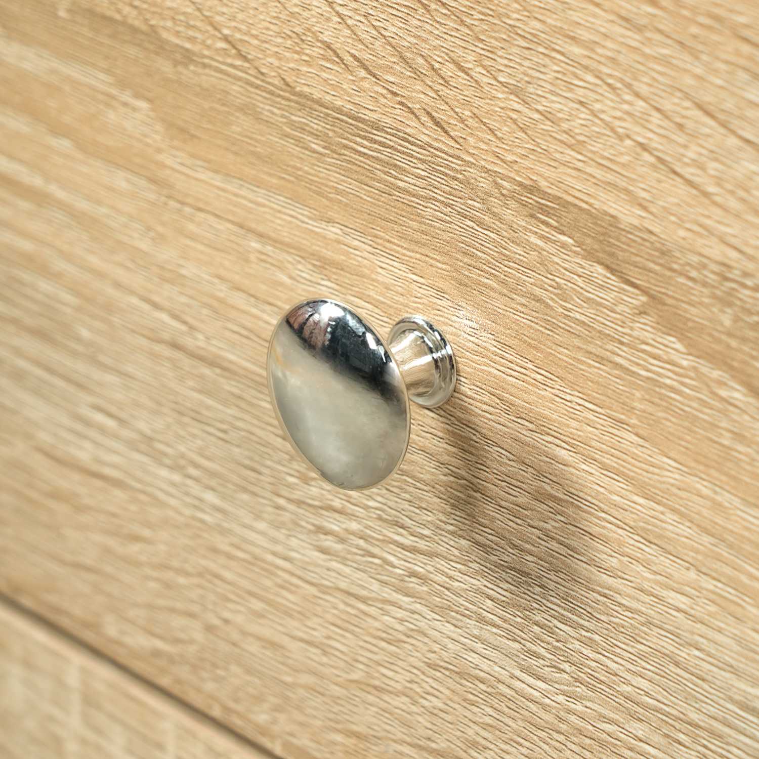 polished silver chrome drawer knob detail on natural oak wood bathroom vanity cabinet
